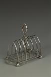 AN EDWARDIAN TOAST RACK of Gothic arched form, with a loop carrying handle, on ball feet, by