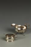 A GEORGE III MUSTARD POT of oval form with bright engraved frieze, blue glass liner and later