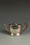 A GEORGE III TEAPOT AND MATCHING STAND of oval form, with a wood scroll handle, geometric frieze,