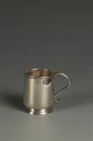 A GEORGE I MUG of small proportions, circular form, reeded scroll handle on a spreading circular