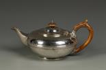 A WILLIAM IV TEAPOT of compressed circular form, with wood handle and finial, crested, with a