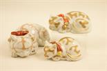 Three Japanese Kutani sleeping cats, each decorated in colours and gilt against a white ground,