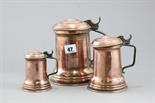 Three Copper Graduating Lidded Tankards with Brass Handles