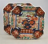 A pair of Japanese Imari square dishes with chamfered edges decorated with flowers in vases,