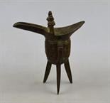 A Chinese bronze jui with long spout and upright handles on the rim, the body cast with taotie, c.