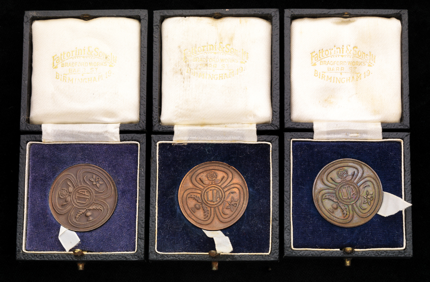 Three cased bronze Lawn Tennis Association junior prize medals,
i) a runners-up medal for the boys