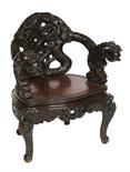 A PROFUSELY CARVED CHINESE ARMCHAIR,
the arms modelled as dragon heads with serpentine seat. (1)