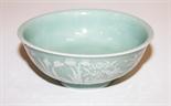 A CHINESE RELIEF MOULDED CELADON GROUND BOWL,
with Qianlong mark, possibly of the period,