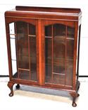 A 1930s walnut glazed two door display cabinet raised on squat cabriole legs.