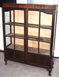 An early 20th century mahogany two door glazed display cabinet raised on squat cabriole legs,