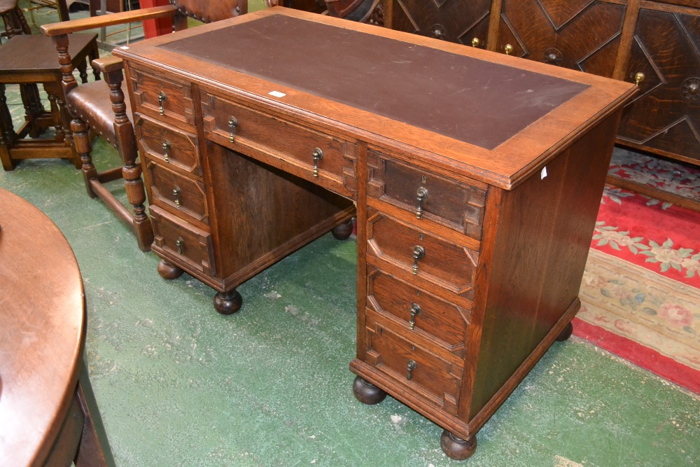 An oak kneehole desk, with an arrangement of nine drawers, turned bun