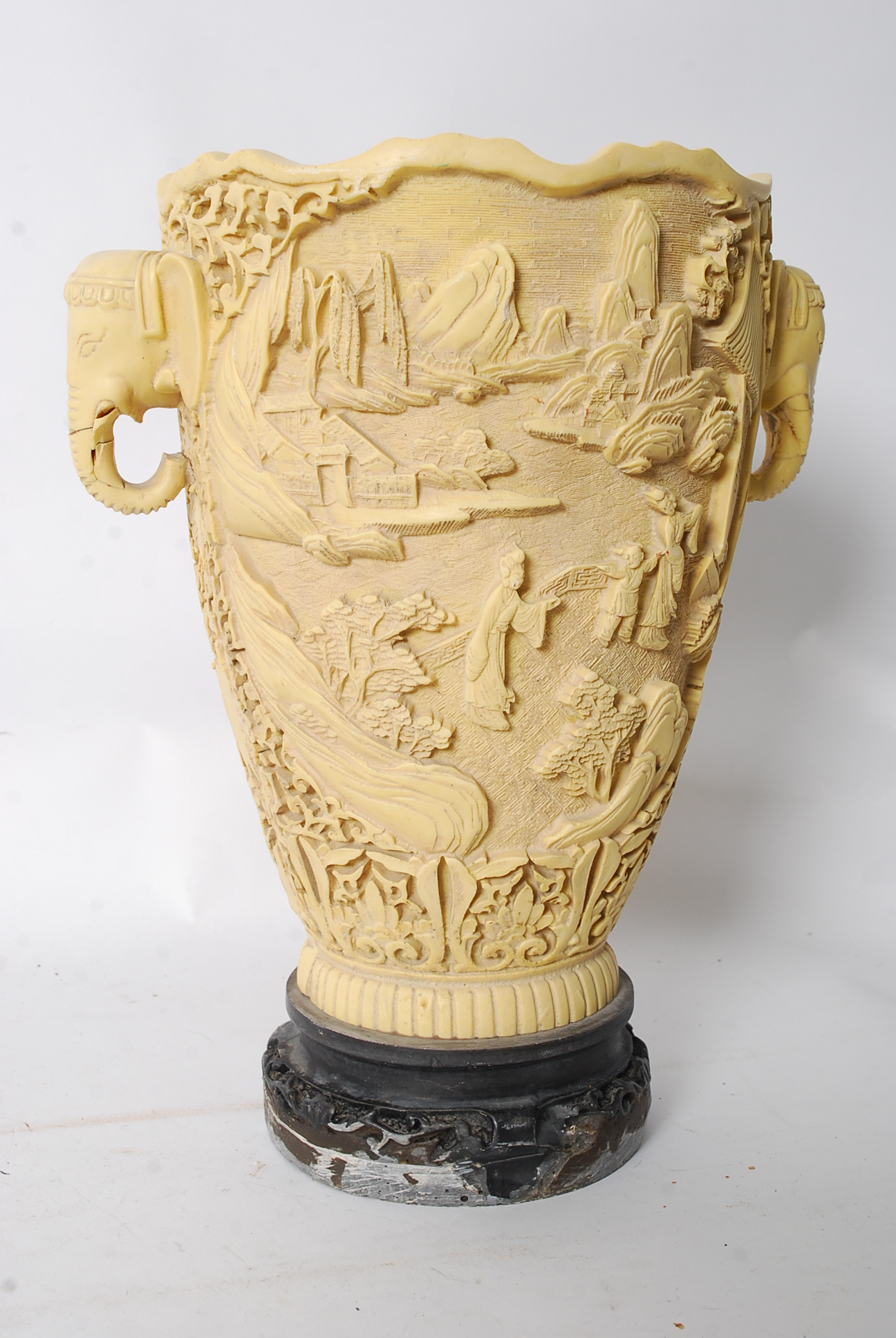 A Chinese carved resin vase heavily decorated in relief being raised on
