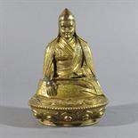 A GILT BRONZE FIGURE OF A LAMA: Tibet, c.1800 Seated on a single lotus throne, the elderly man with