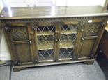 Oak floor standing show cabinet with 2 lead glazed doors to the front, flanked by twin cupboards 4`