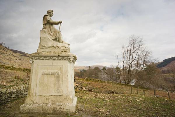 Image of James Hogg was born in a small cottage on Ettrickhall Farm at the top of the Ettrick Valley in 1770. He was the second son of Robert and Margaret Hogg (nee Laidlaw). Robert Hogg tried farming but soon became bankrupt and at the age of six, James had to leave school to perform the most menial tasks of farm service. 

At the age of eleven, he became a shepherd watching the flocks as they grazed on the unfenced hills. While there, he practised reading with the encouragement and use of his master's library. By the time he was eighteen he could read proficiently, and write well but slowly at twenty-four. 

Although he had little formal education, Hogg was fortunate in his family connections. His mother and her family had a great fund of the oral traditions of the Border Ballads, the folklore and superstitions of the country people. His father was of Covenanting stock and from his side of the family, Hogg observed the effect of over-zealous Calvinism. 

This background was his basic material as a poet, storyteller and songwriter. 

With most of his life spent in the hill country, familiar stories, places and people appear in his works, often thinly disguised. Hogg was a collector of the oral and musical traditions of the Borders and when a young lawyer called Walter Scott was seeking fragments of ballads in the Ettrick Forest in 1801, it was little wonder that he asked Jamie the Poeter to be his guide. This was to be the start of a friendship which lasted until Scott's death in 1832. 
Hogg had published in his own right but Scott introduced him to the literary establishment of the Edinburgh Enlightenment. Soon Hogg was taking his place amongst them as their equal or even superior in published prose and poetry. 

His epic poems The Queen's Wake', Mador of the Moor and 'Queen Hynde' bear comparison to any, while his The Confessions of a Justified Sinner' is recognised as a major prose work of the century. 

Many of the literati of Edinburgh professed to look down on the unlettered countryman while still being envious of his talents. Hogg probably knew this and played up to his country shepherd image as he describes himself in The Queen's Wake. 

"But when the bard himself appeared, 
The ladies smiled, the courtiers sneered 
For such a simple air and mein 
Before the court had never been 
A clown he was, bred in the wild, 
And late from native moors exiled". 

As well as being a literary success, Hogg had a constant ambition to the higher praise in Ettrick Forest of being 'a farmer'. Here, he was much less successful; money made by his pen was lost in a series of farming failures. Such was his determination to be seen to have made good in the eyes of his neighbours, that when Sir Walter Scott obtained two seats for himself and Hogg at the Coronation of George IV in Westminster Abbey, Hogg refused on the grounds that it was at the same time as the great St Boswells Fair and no new farmer could afford to miss that. 

James Hogg married Margaret Phillips in 1820 at the age of fifty. When he died fifteen years later, he left a family of one son and four daughters. After a space of twenty years, his widow received a yearly pension of £100 until she died in 1870.