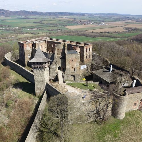 Overall view of the fringe of Podhůra Quarry, from the west, into the valley of Bečva Gate. The upper part of the image shows the Maleník Massif marked with Heflštýn Castle, the guardian of the Moravian Gate. The municipality of Týn nad Bečvou spreads over the foot of the castle hill. On the left: the skyline shows the Odra Highlands framing the northern border of the Bečva Gate. 