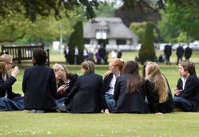 Girls relaxing on the South Front lawns, the cricket pavilion in the background