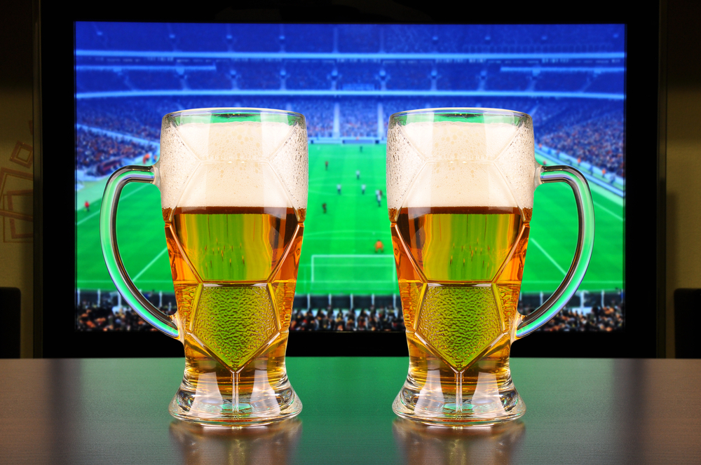 Glasses of beer in front of Football on TV