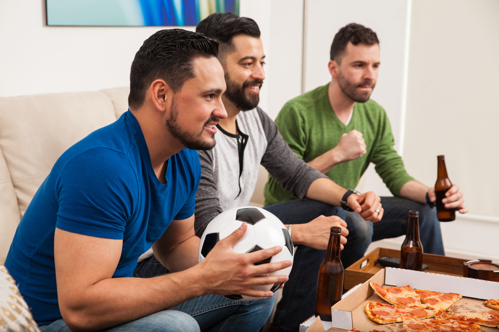 People drinking beer and eating pizza while watching football