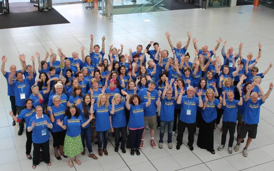 A large group of NNF volunteers with their hands raised in the air.