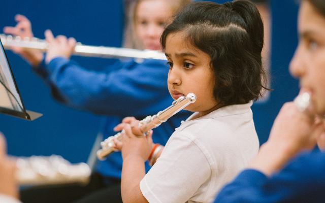 A school child plays the flute as part of Opera North's In Harmony education programme