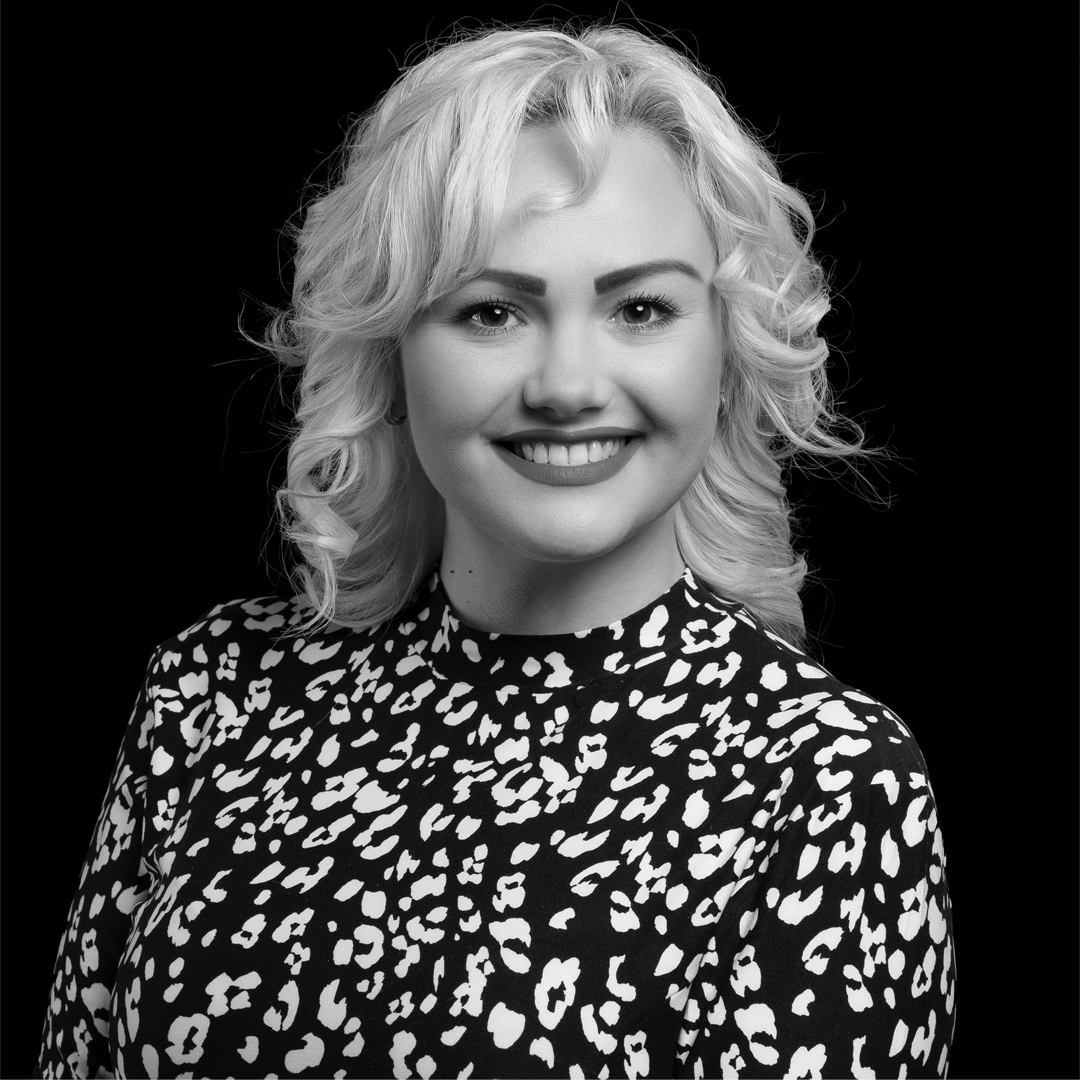Inna-Gusieva-BW-1080x1080 A white woman with curled blonde hair wearing a black and white top.