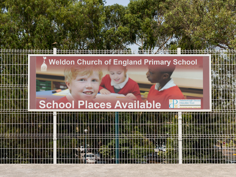 horizontal-banner-mockup-hanging-from-a-fence-at-a-school-a10572.png
