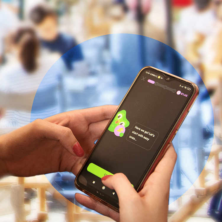Photograph: woman holding her phone and using the duolingo app