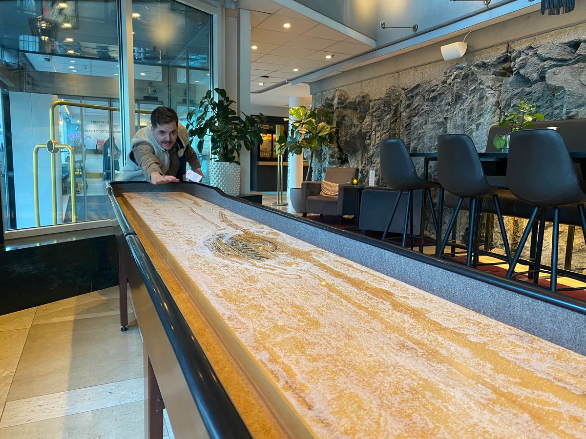 man playing shuffleboard in hotel bar