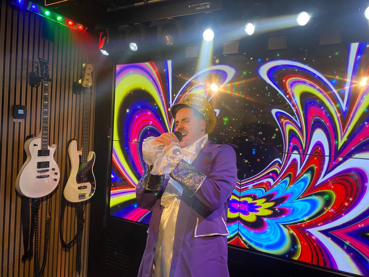 A man singing karaoke in a private karaoke room, dressed in costume. Singa