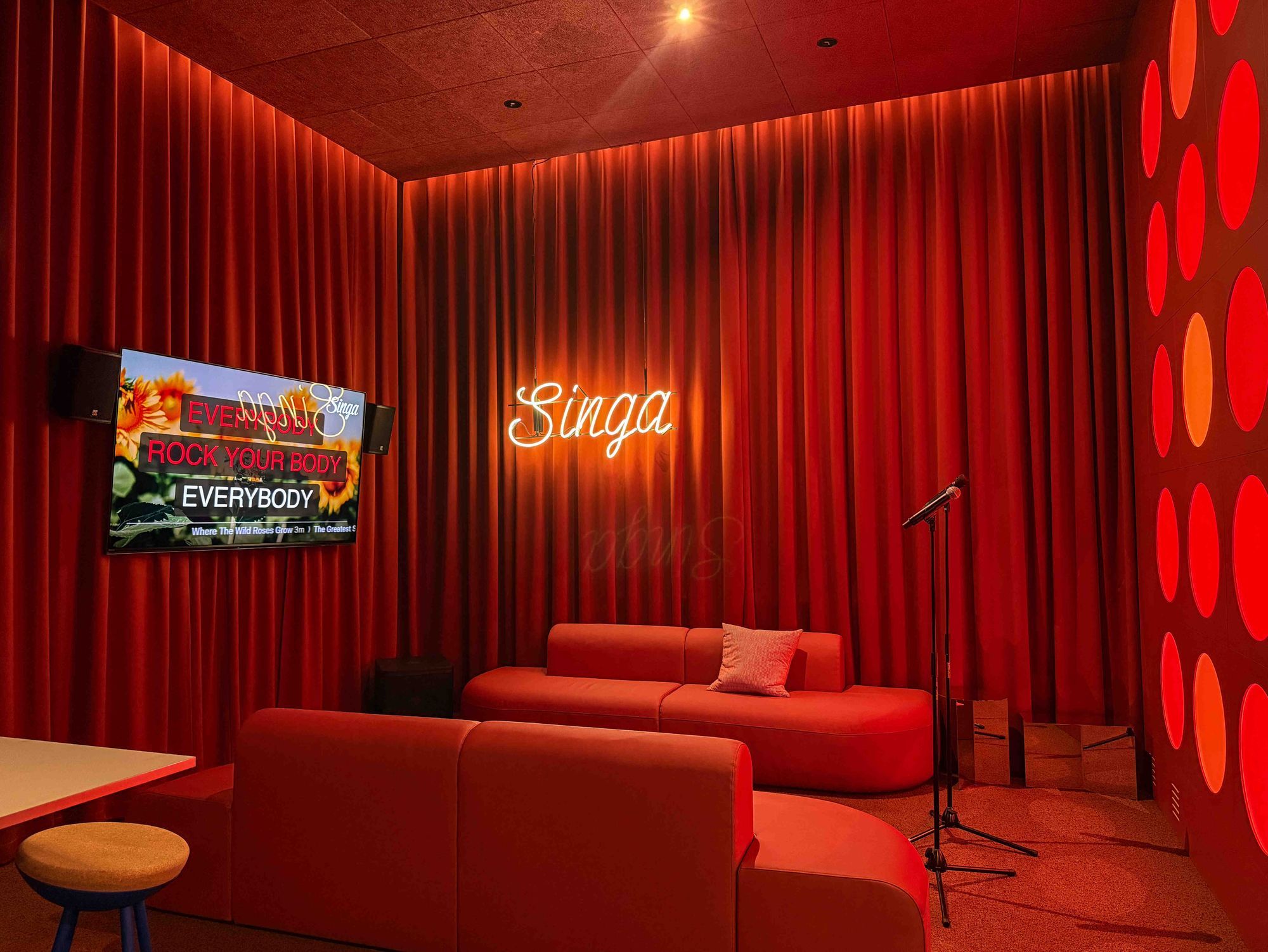 Lange Vorhänge rahmen den Raum elegant ein und dämpfen gleichzeitig die Akustik, wodurch sowohl eine stilvolle Kulisse als auch eine intime Atmosphäre für Karaoke-Abende geschaffen wird.