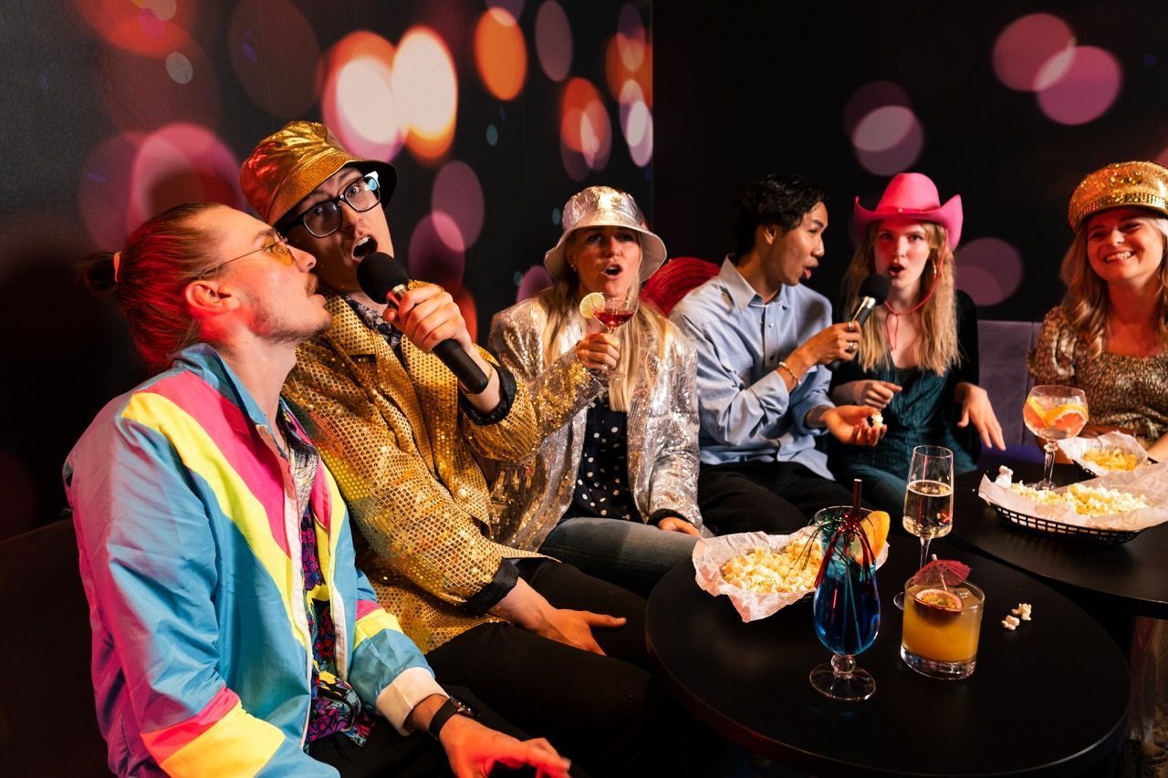 Eine kostümierte Gruppe singt Karaoke in einem Karaoke-Raum.