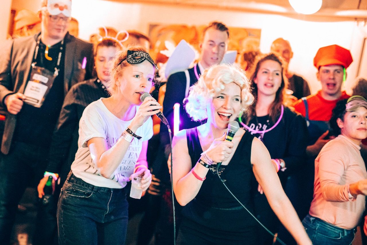 People at a themed party singing karaoke on a cruise ship.
