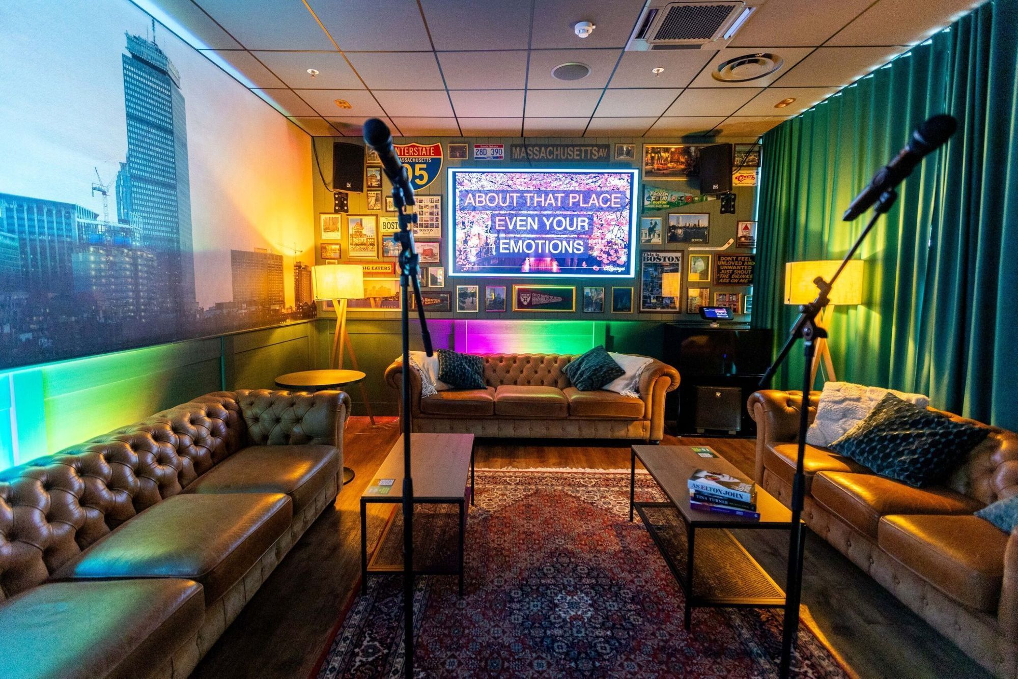 Ein Karaoke-Raum mit Sofas, angenehmer Beleuchtung einem großen Bildschirm und Mikros.