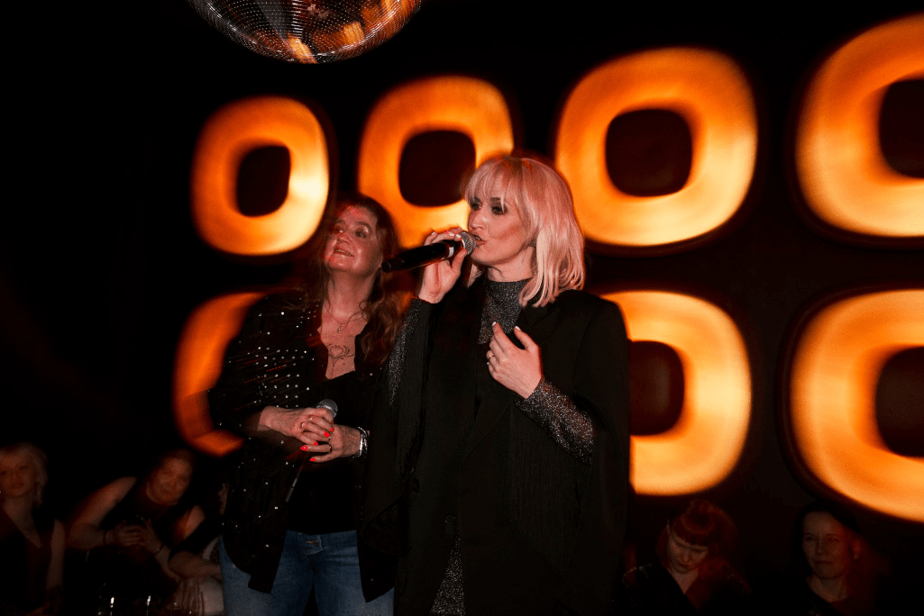 Maija Viilkkumaa singing karaoke with a fan at the Karaoke Queen Event in ÅKE Karaoke