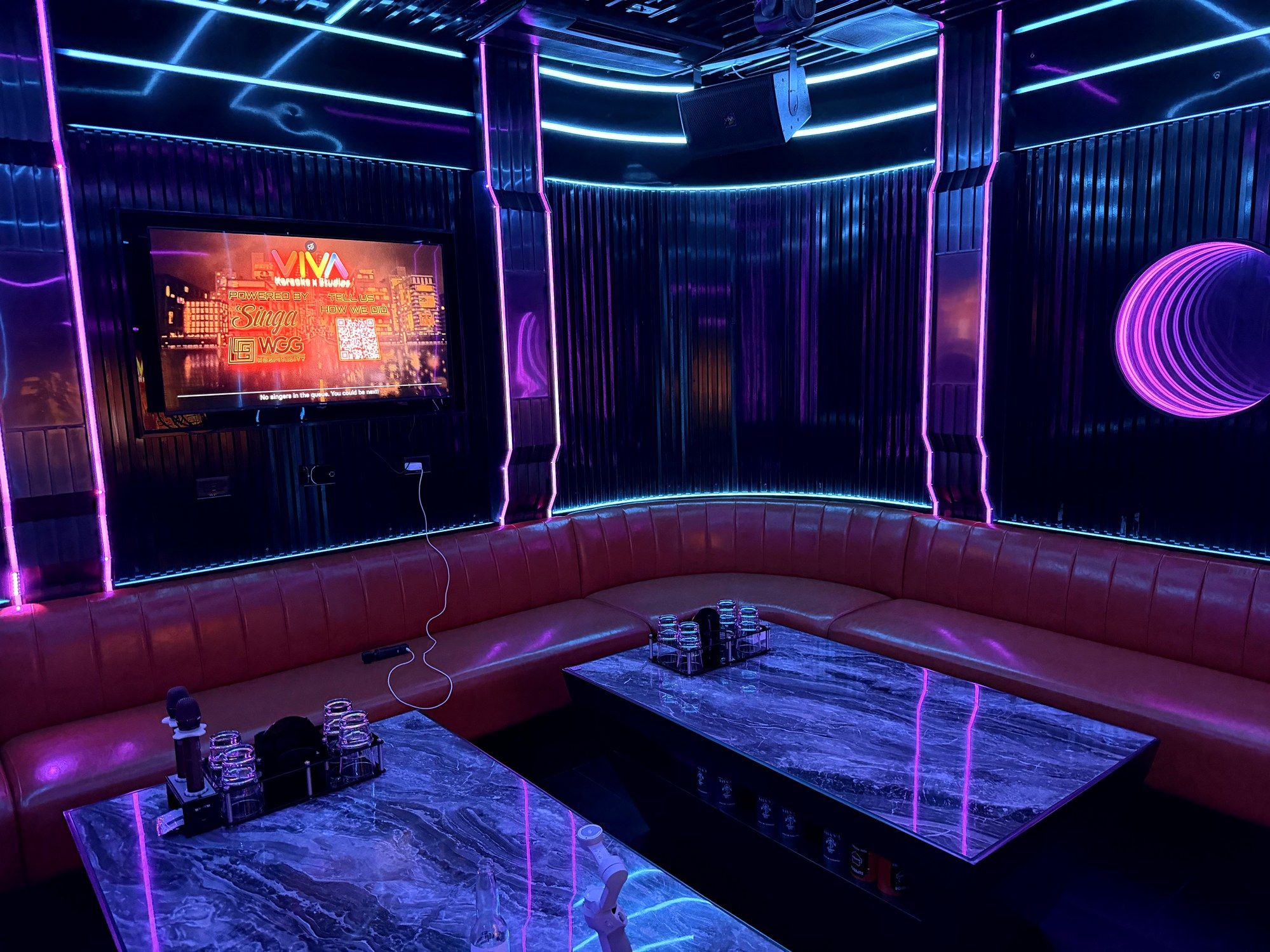 Empty private VIP room at VIVA Karaoke with marble tables, leather banquette, and neon mirrors, freshly reset.