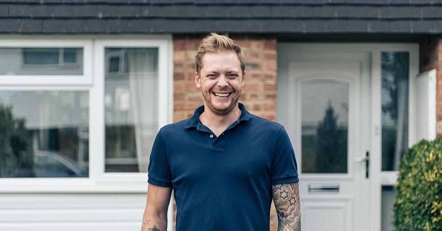 Man smiling in front of a house