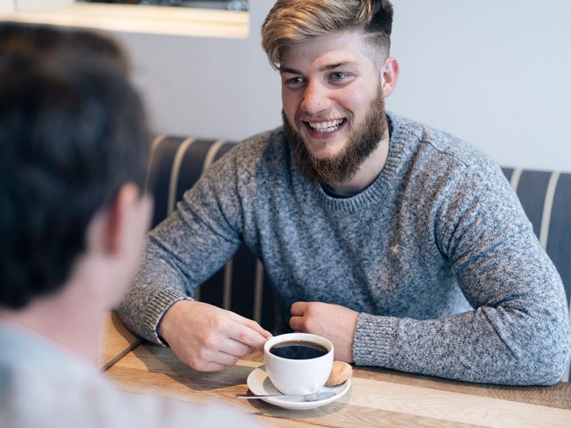 Ben smiling in a cafe with coffee