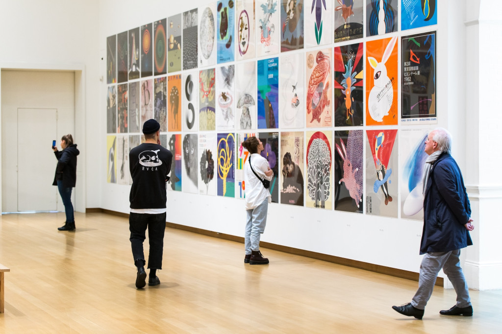 photo of visitors looking at a wall with colorful posters