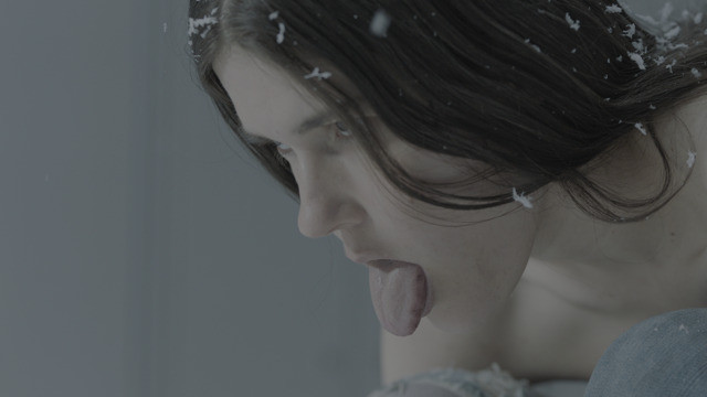 Anne Imhof, 13th Februar, 2022 (video still), person with tongue out their mouth and snow falling on black hair