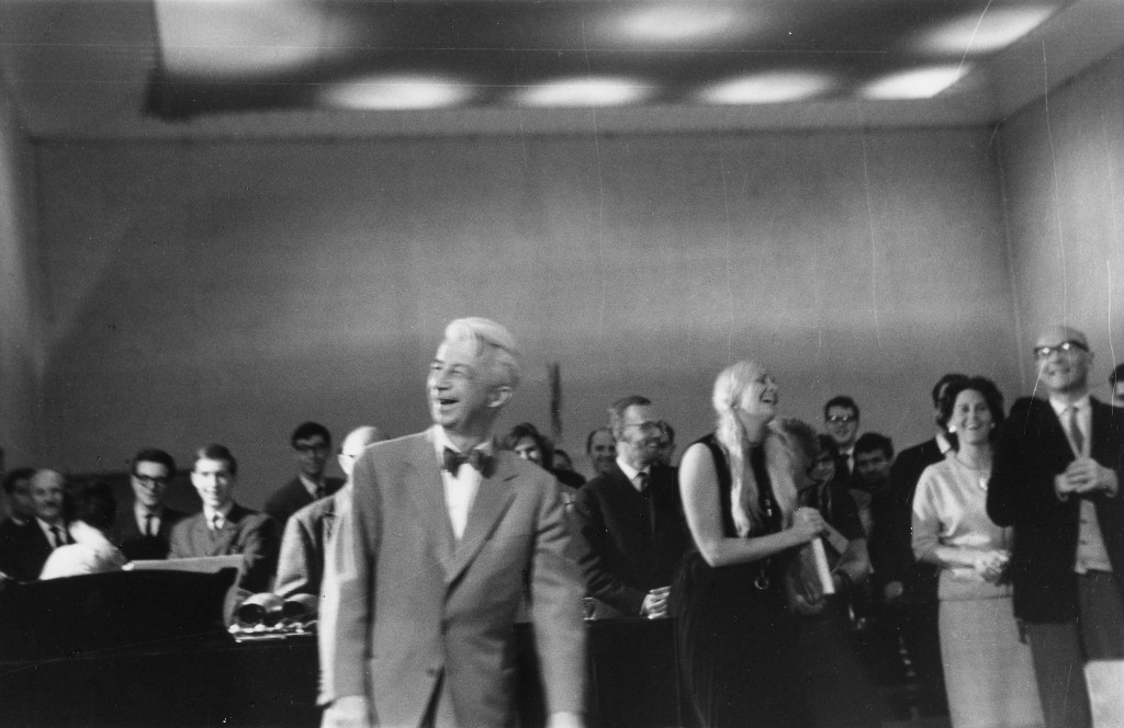 zwartwit foto van Willem Sandberg lachend, en Mary Bauermeister erachter