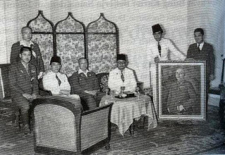 Meeting with Japanese officials, including General Imamura (seated, center), with Sukarno in Jakarta. The painter Basoeki Abdullah is holding the painting being presented, Portrait of General Imamura, 1942. Source: Aiko Kurusawa