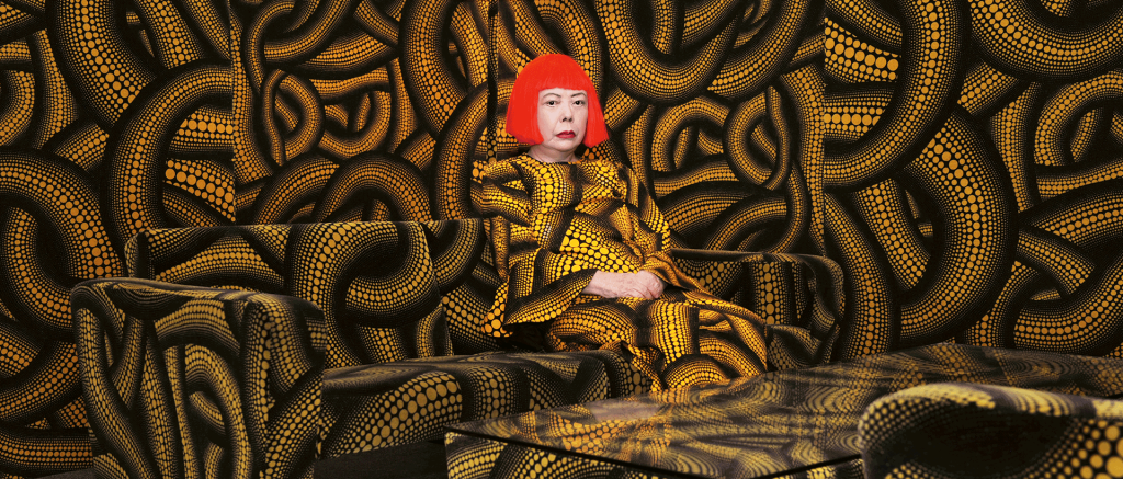 photo of Yayoi Kusama in a room with yellow and black dots