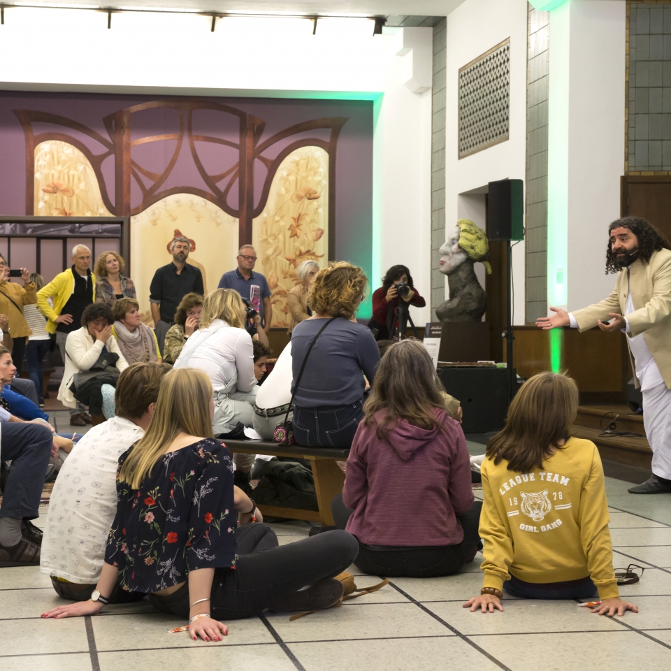 Man vertelt verhaal in het museum aan een groep bezoekers tijdens de museumnacht in het Gemeentemuseum Den Haag