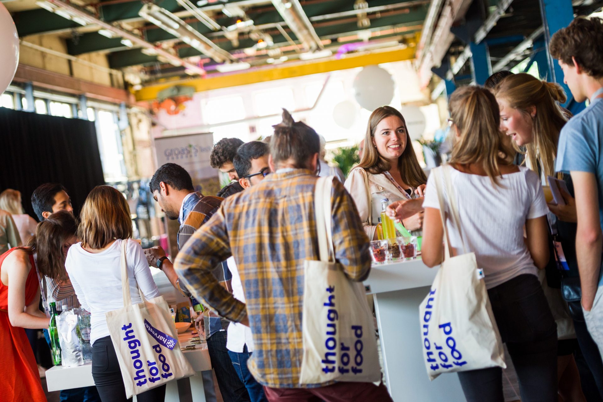 TFF Summit participants cheerfully talking to each other, Thought For Food branded bags