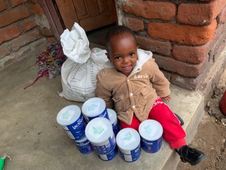 Toddler surrounded by infant formula tins