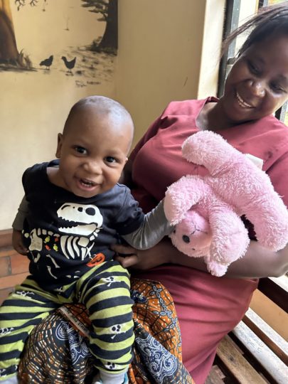 A baby smiling with his carer and toy