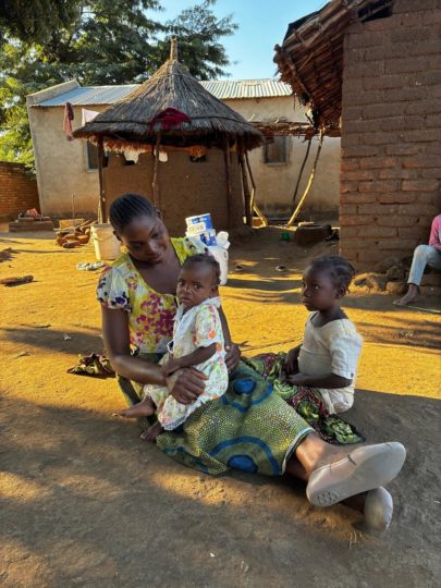 A baby and child with their guardian in their village