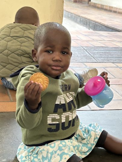 A child eating a biscuit and holding a sippy cup
