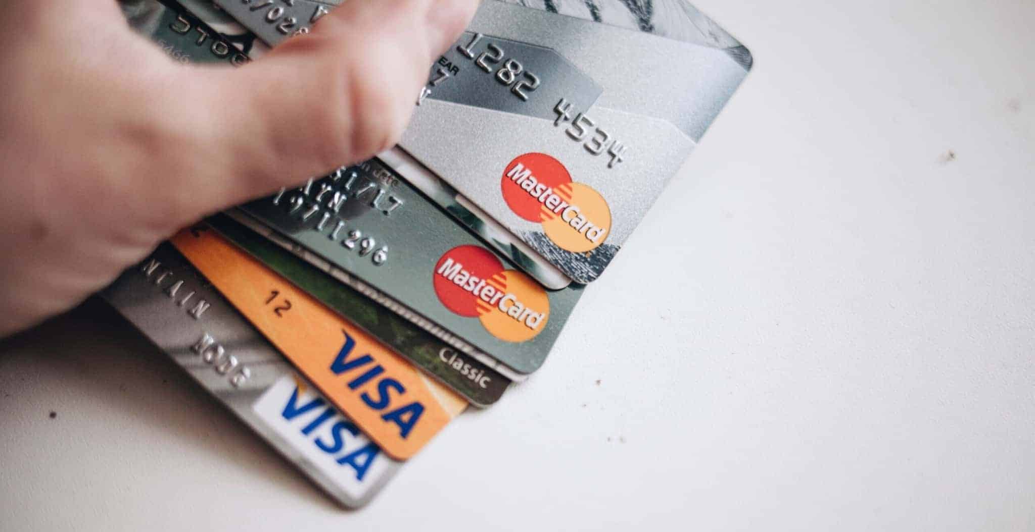 mão de pessoa segura vários cartões de crédito visa e mastercard